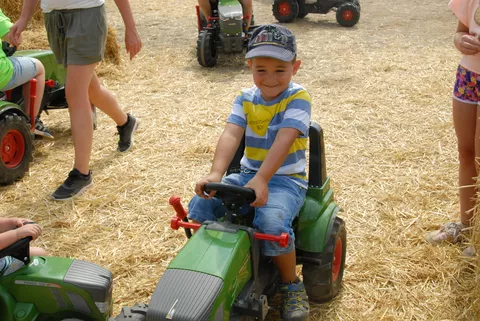 Das Kind freut sich auf dem Fendt Trettraktor sitzen zu dürfen