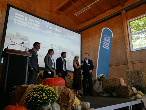 Besucher sitzen in einer Halle und schauen sich die Eröffnung der Swiss Future Farm an