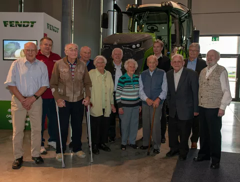 Ehemalige Mitarbeiter stehen vor einem Fendt Traktor