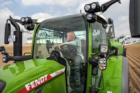 Mann sitzt in Fendt 724 Vario auf FendtONE Terminal schauend und beim befahren eines Feldes