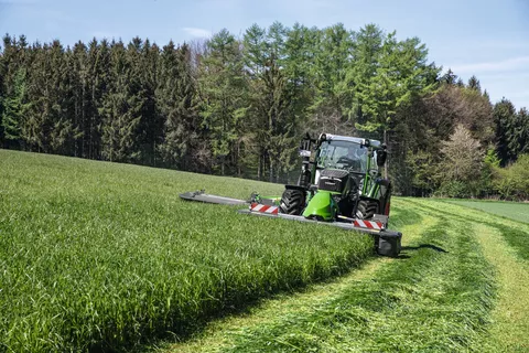 Fendt 516 Vario mit Fendt Slicer 310 F und Heckmähwerkanbau mäht bei schönem Wetter eine Wiese