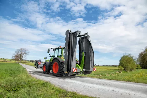 Fendt Traktor mit Fendt SafetySwing zur EInklappung des Fendt Slicer 860 fährt auf einer Straße