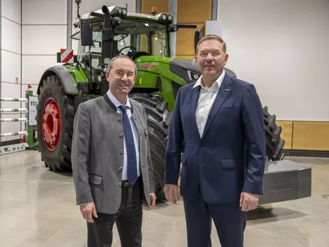 Zwei Männer stehen vor einem Traktor in einer Ausstellungshalle