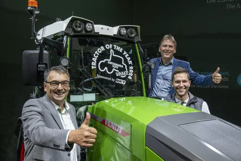 Drei Männer stehen um einen Fendt Traktor und halten ihre Daumen nach oben. Sie freuen sich, weil sie einen Preis gewonnen haben.