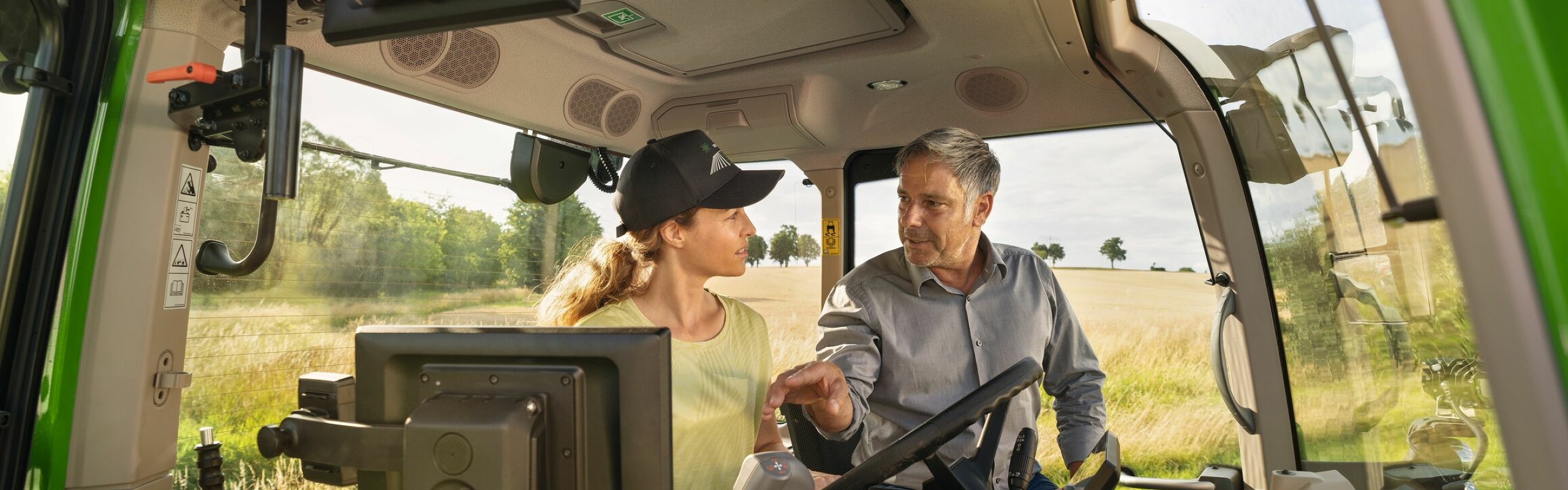 Fendt Händler berät Landwirtin auf einem Fendt Traktor zu allen Fendt Services