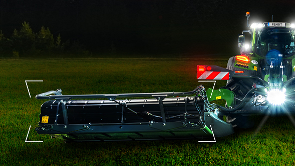 Ein Fendt Traktor steht mit einem Fendt Slicer Mähwerk auf einer grünen Wiese.