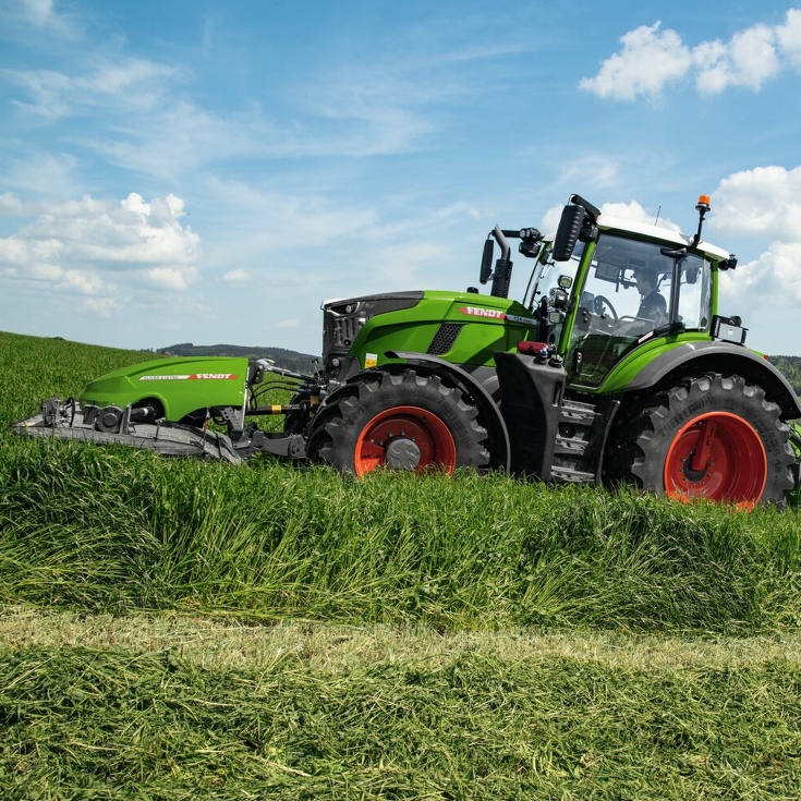 Seitliche Aufnahme, wie ein Landwirt mit einem Fendt Slicer eine Wiese mäht.