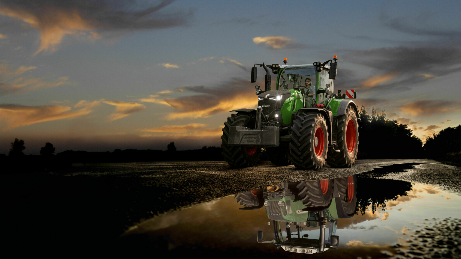 Ein Fendt 700 Vario Gen7 auf der Straße vor dramatischem Sonnenuntergangshimmel