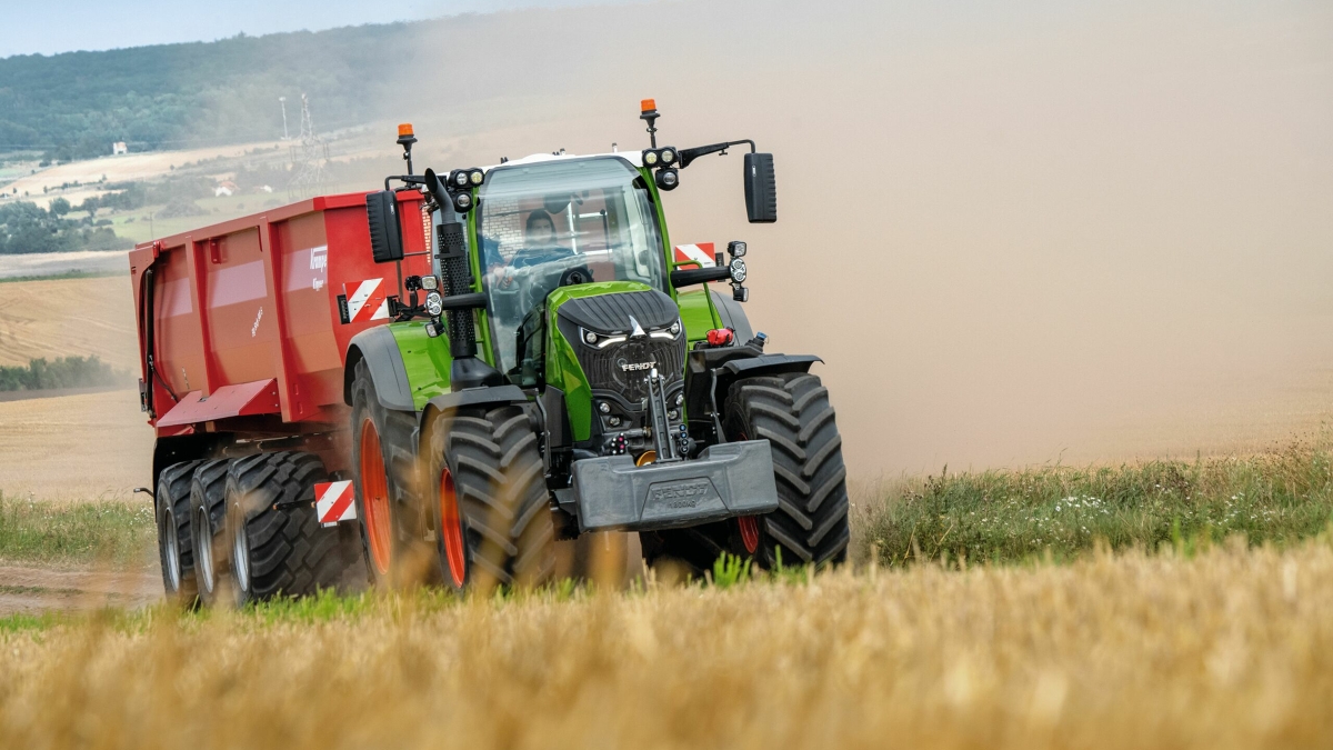 Ein Fendt 700 Vario Gen7 beim Transport mit einem roten Ladewagen.