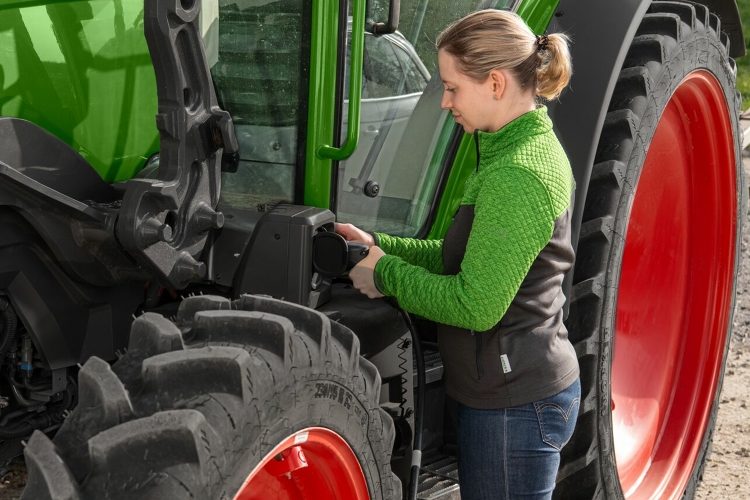 Eine Landwirtin steckt ihren E-Traktor zum Laden an