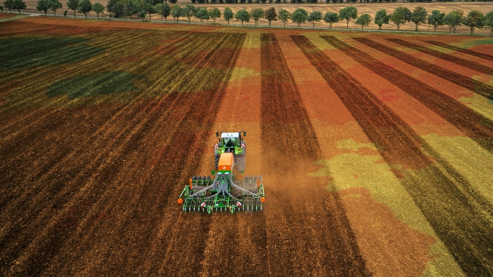 Ein grüner Fendt Traktor mit Anbaugerät bei der präzisen Bodenbearbeitung dank FendtONE Maschinensteuerung