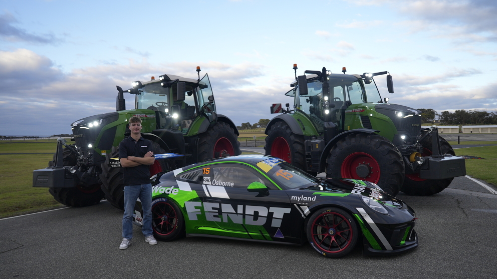 Clay Osborne standing in front of two green Fendt tractors and his Porsche racing car with the Fendt logo