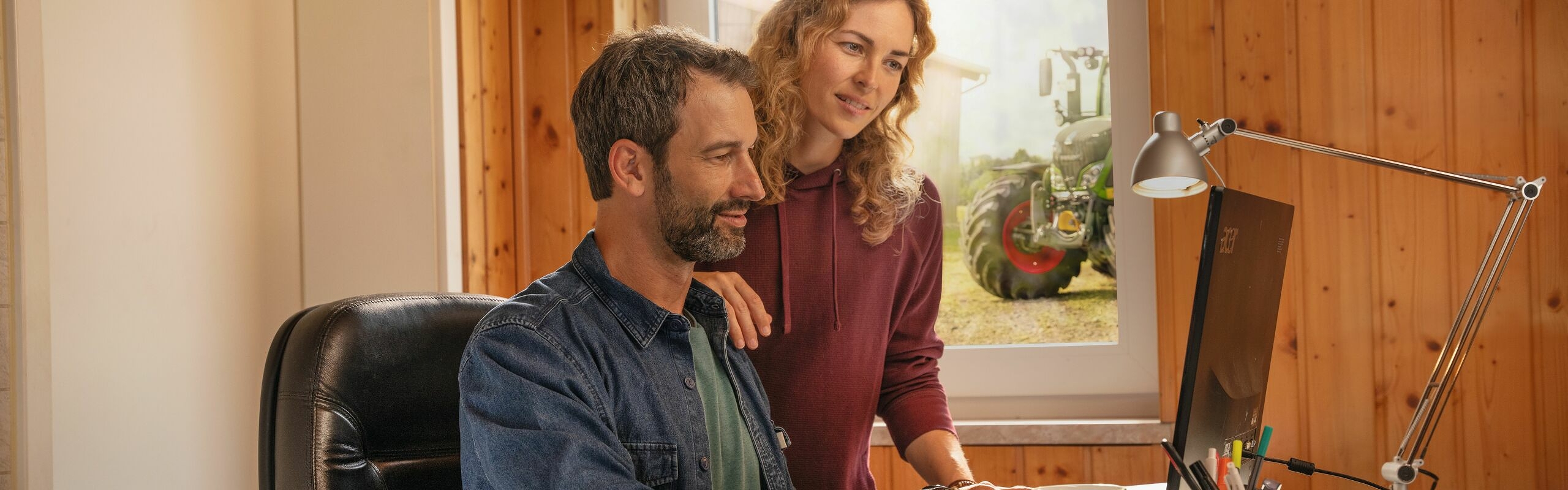 Um casal de agricultores na frente de seu computador, no escritório, criando limites de campo com a agronomia FendtONE