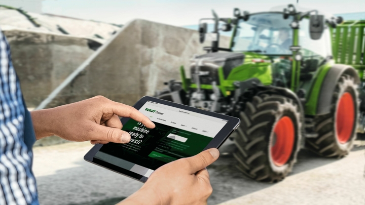 Close-up de um tablet na mão de um agricultor verificando os dados de sua máquina central na tela via Fendt Connect