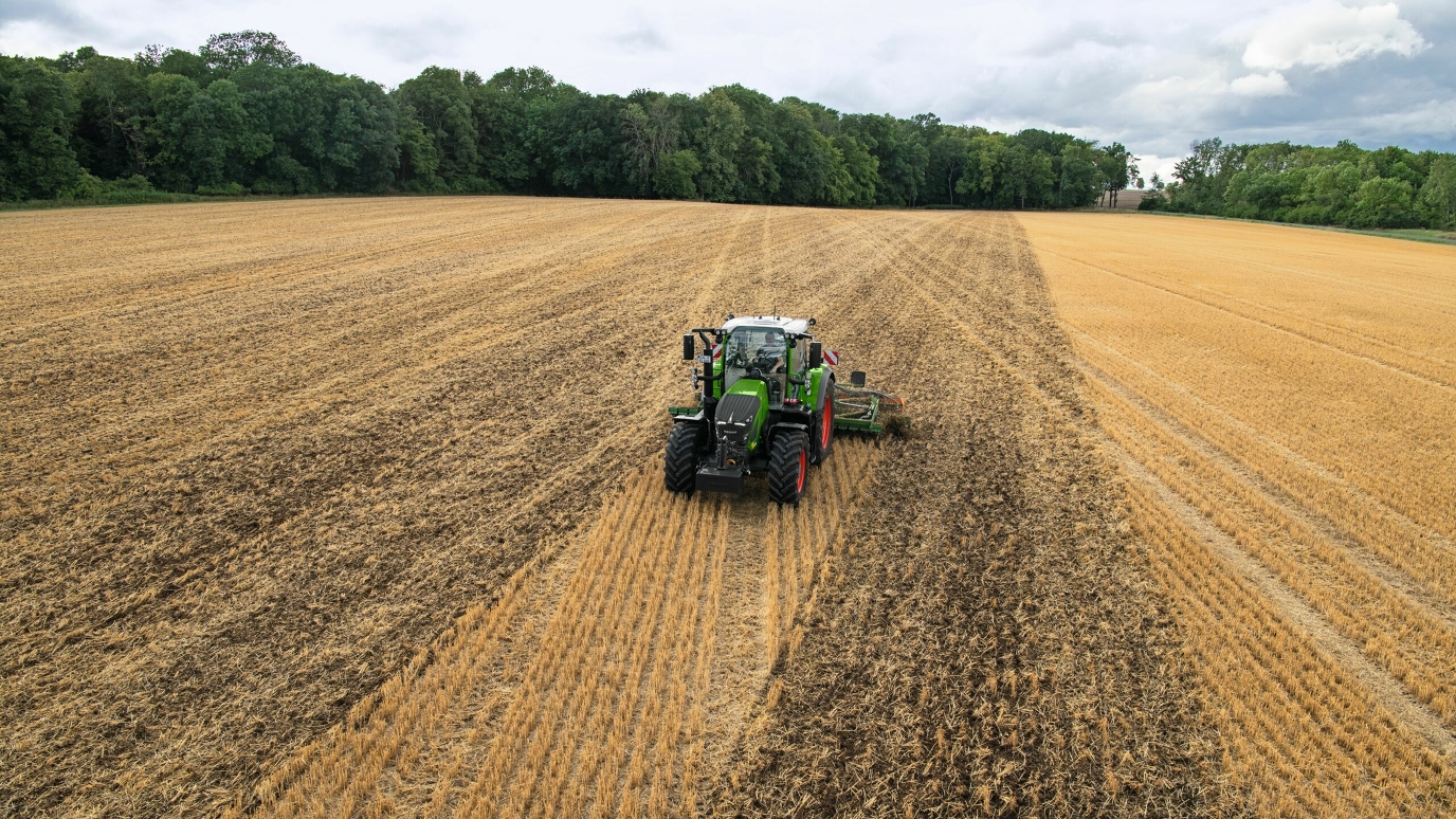 Um trator verde da Fendt com bordas vermelhas que trabalham o solo no campo usa a orientação de ângulo A+