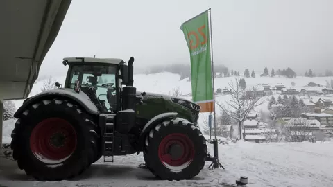 Schneebedeckte Landschaft mit einem Fendt Traktor im Vordergrund