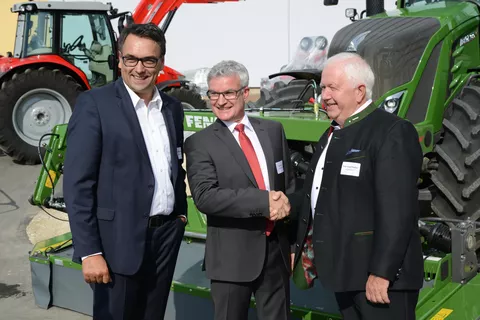 Drei Männer vor einem Fendt Traktor, zwei davon schütteln Hände