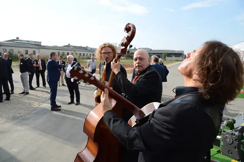 Drei Musiker spielen Instrumente auf dem Gelände