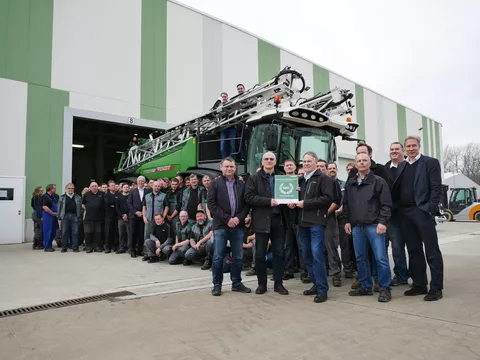 Viele Menschen stehen vor der Pflanzenschutzspritze Fendt Rogator 600. Zwei Männer im Vordergrund halten eine Urkunde in die Höhe.