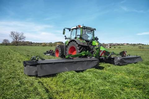 Fendt 516 Vario mit Fendt Slicer 860 und Frontmähwerkanbau mäht bei schönem Wetter eine Wiese