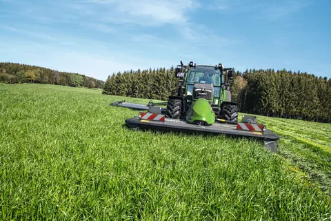 Fendt 516 Vario mit Fendt Slicer 310 F und Heckmähwerkanbau mäht bei schönem Wetter eine Wiese