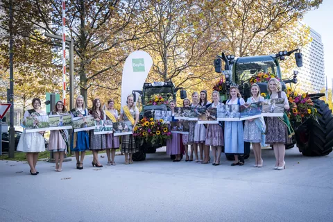 Die Damen mit ihren Kalendern neben mit Blumen geschmückten Fendt Traktoren