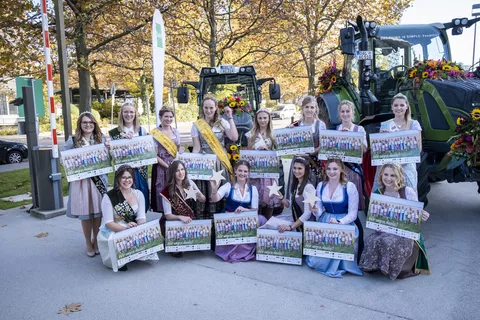 Die Damen mit ihren Kalendern neben mit Blumen geschmückten Fendt Traktoren