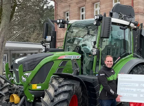 Ein Mann steht vor einem Fendt Traktor und lächelt