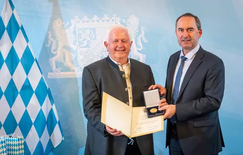 Peter-Josef Paffen erhält die Bayerische Staatsmedaille von Hubert Aiwanger (Bayerischer Staatsminister für Wirtschaft, Landesentwicklung und Energie) im Hintergrund eine bayerische Flagge