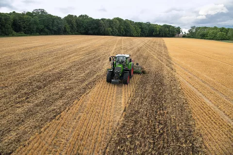 Ein Fendt Traktor mit einer Scheibenegge fährt über ein Stoppelfeld