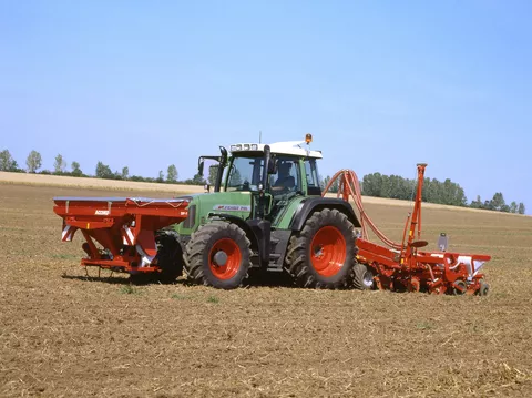 Fendt 716 Vario Gen3 bei der Aussaat mit einer roten Sämaschine