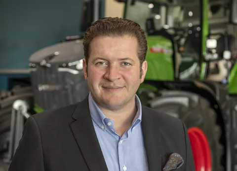 Portrait von Dr. Dominic Esser vor einem Fendt Traktor