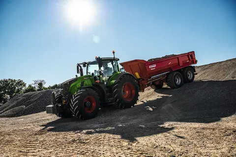 Ein Fendt 728 Vario fährt mit einem Krampe Kipper in rot einen Hügel auf einer Baustelle hinab