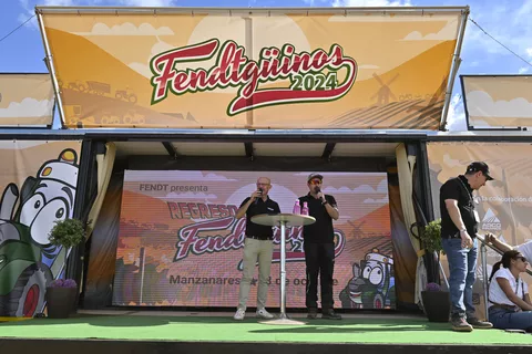 Juan Mari Guajardo, Sprecher der Vuelta Ciclista a España und offizieller Sprecher der Fendtgüinos und Mario Lallana, Product Engineer bei Fendt stehen auf einer Bühne vor dem Fendtgüinos 2024 Logo und moderieren die Vorführungen