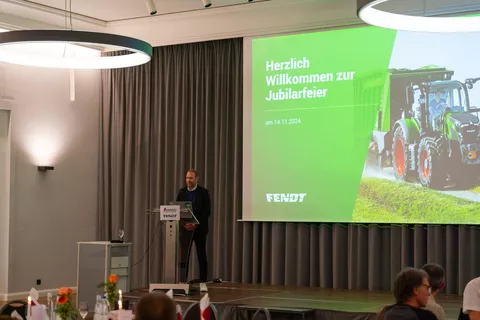 Jochen Gnann (Werksleiter Fendt Asbach-Bäumenheim) auf einer Bühne begrüßt die Gäste in einem Saal der Alten Brauerei in Mertingen