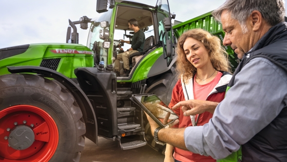 Ein Fendt Händler zeigt einem Kundenpaar die Optionen zur Finanzierung eines 700 Vario Traktors