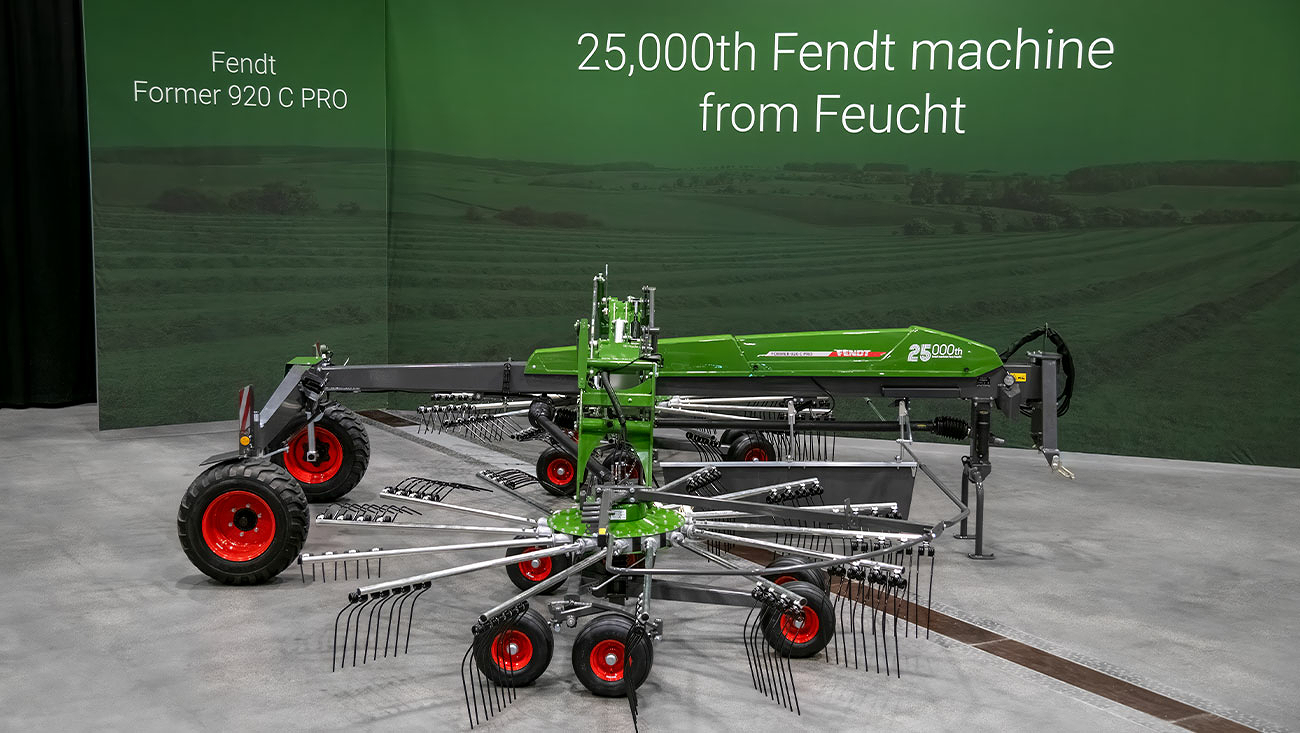 Ein Fendt Former 920 C Pro steht vor einer gründen Tafel mit dem Aufdruck "25,000th Fendt machine from Feuch".