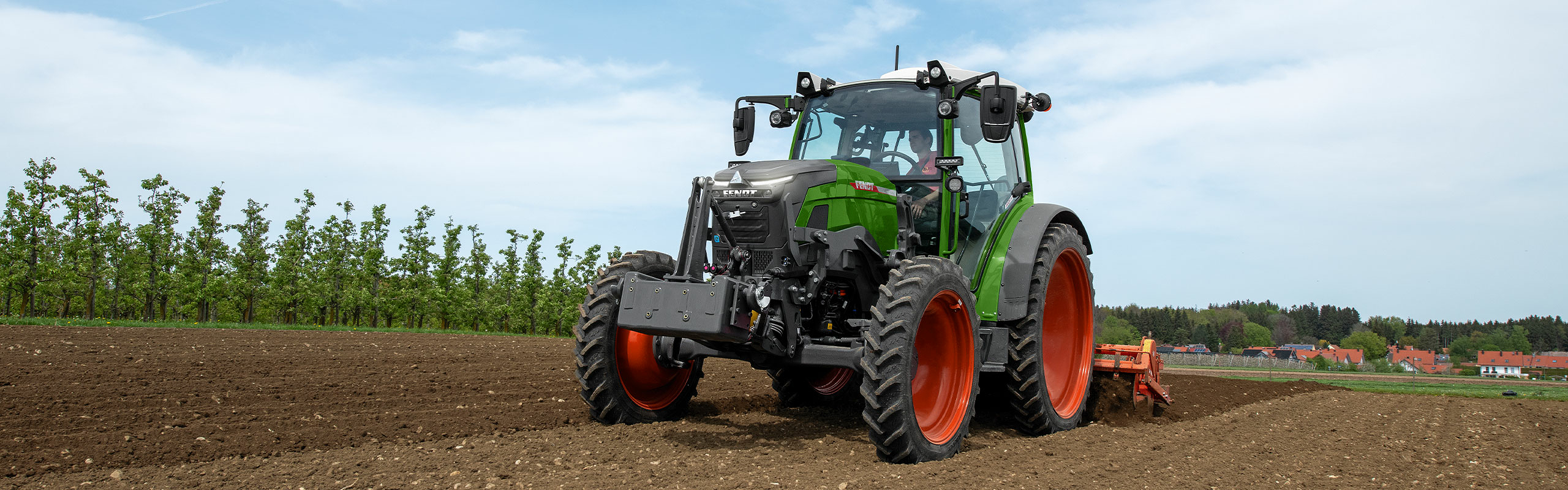 Ein Fendt e100 Vario im Feld bei der Bodenbearbeitung