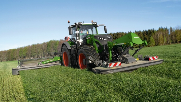 Ein Landwirt mäht mit einem Fendt Traktor und Fendt Slicer Frontmähwerk eine grüne Wiese.