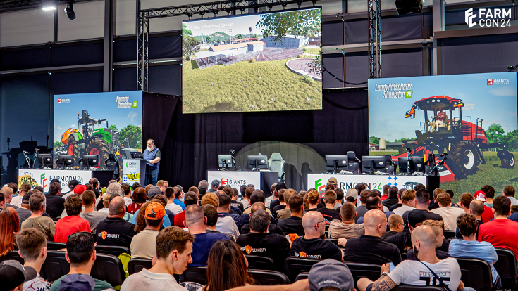 Besucherinnen und Besucher der FarmCon 24 schauen auf die Bühne und eine große Leinwand, wo sie einen ersten Einblick in den neuen Landwirtschafts-Simulator 2025 bekommen