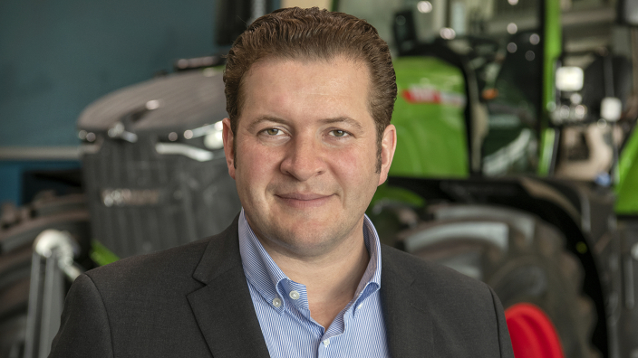 Portrait von Dr. Domonic Esser vor einem Fendt Traktor