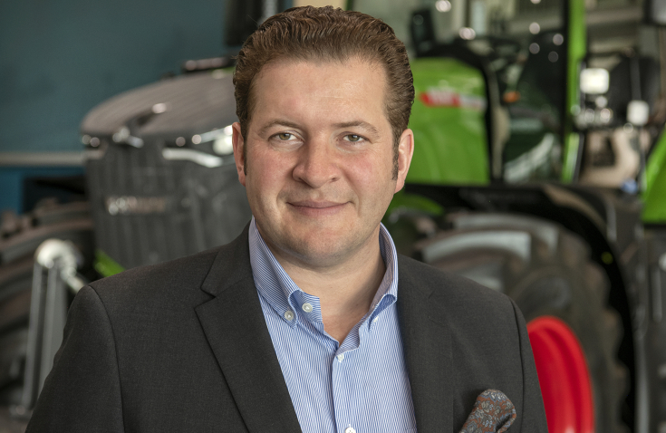 Portrait von Dr. Dominic Esser vor einem Fendt Traktor