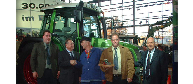 5 Männer vor einem Fendt Farmer 412 Vario bei der Auslieferung des 30.000sten Fendt Schleppers an die Niederlanden im Jahr 2013, der dritte Mann von links mit niederländischer Tracht - blaue Kleidung, Schiebermütze und ein rotes Halstuch