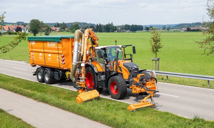 Fendt 728 Vario in kommunal-orange mit zwei Auslegemähern bei Mäharbeiten am Straßenrand und mit einem Anhänger