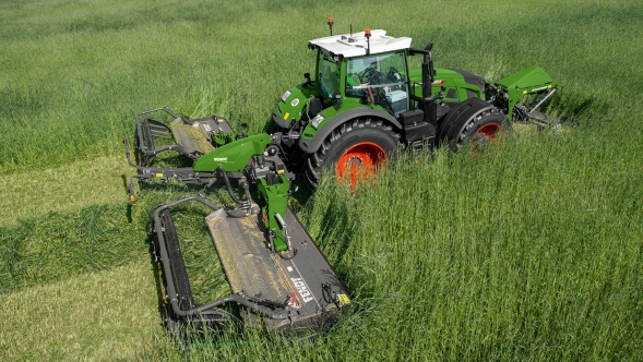 Ein Landwirt mäht mit einem Fendt Traktor und einem Fendt Slicer Front- und Heckmähwerk eine hohe grüne Wiese.