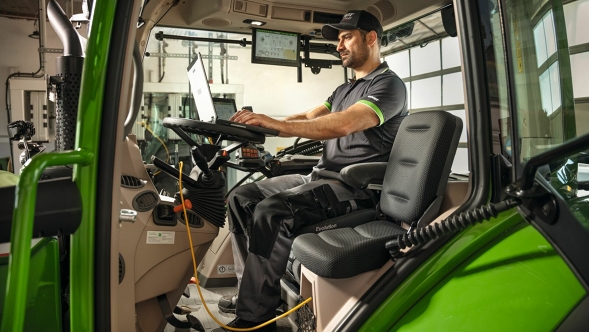 Ein Fendt Servicemitarbeiter schaut sich auf der Traktorkabine Erklärvideos zu FendtONE onboard und offboard an