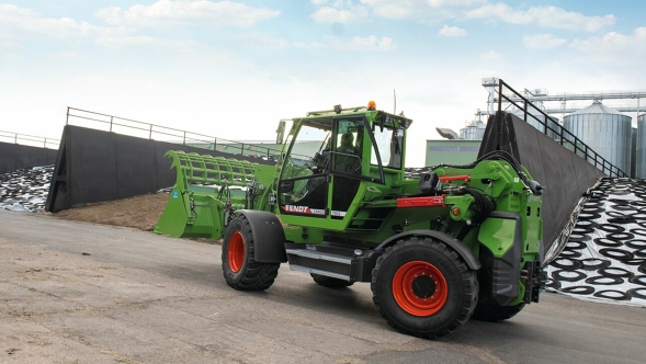 Ein Fendt Cargo T955 steht auf einem Weg vor einem Silo.