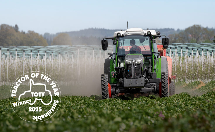 Fendte107 Vario auf einem Erdbeerfeld bei der Strohverteilung zwischen den Erdbeerreihen; unten links ist dasLogo für den Sustainable Tractor of the Year 2025 in weiß platziert