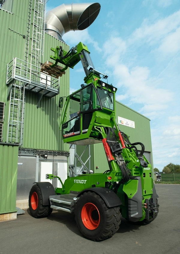 Fendt Cargo T955 mit hochgefahrener Kabineund ausgefahrenem Teleskoparm vor einer Lagerhalle