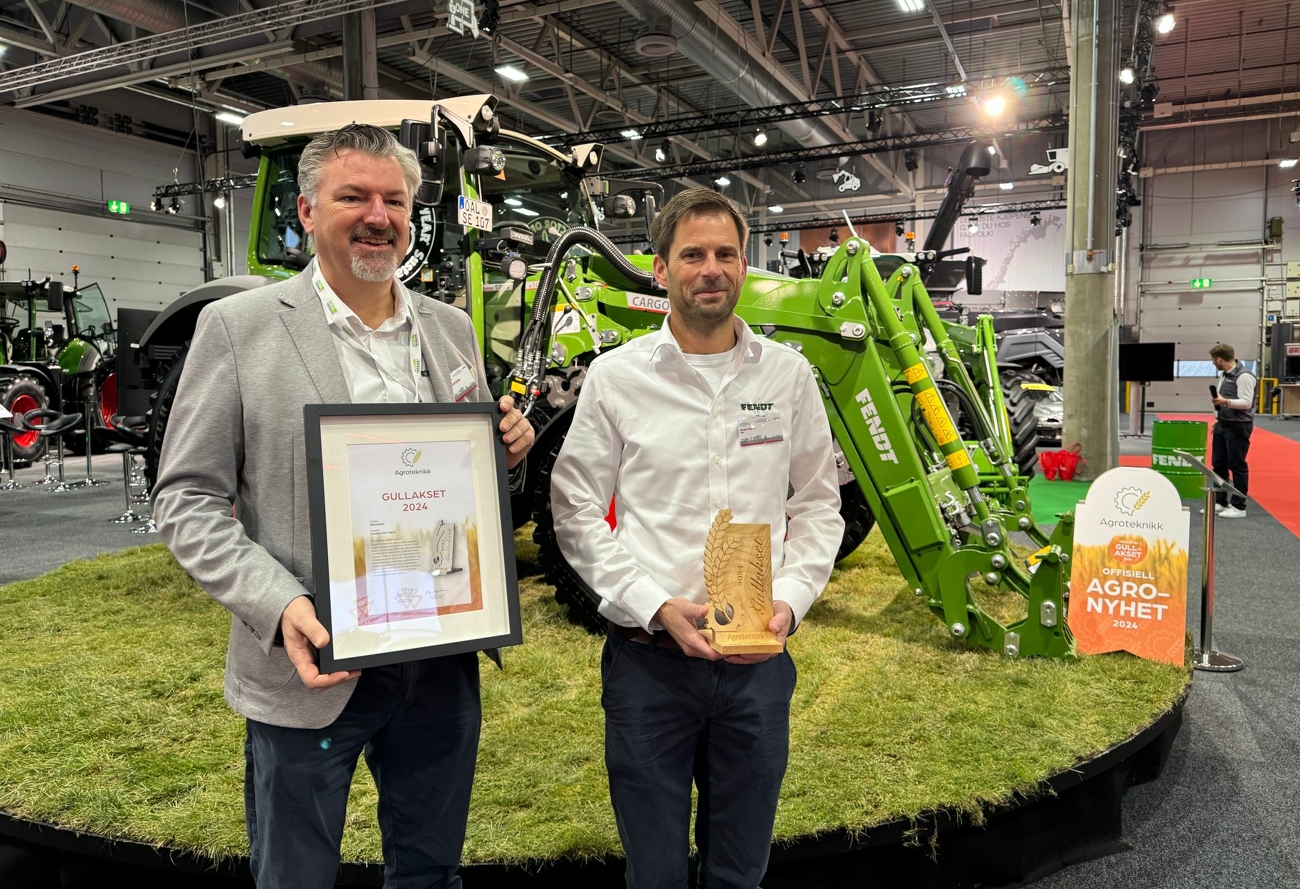 John Henrik Stadler (Business Manager Fendt Norwegen) und Jørgen Skjelin (Retail Manager Fendt Traktoren und Spritzen Norwegen) vor dem Fendt e100 Vario freuen sich über den Gullakset Award 2024 in Gold auf der norwegeischen Messe Agroteknikk